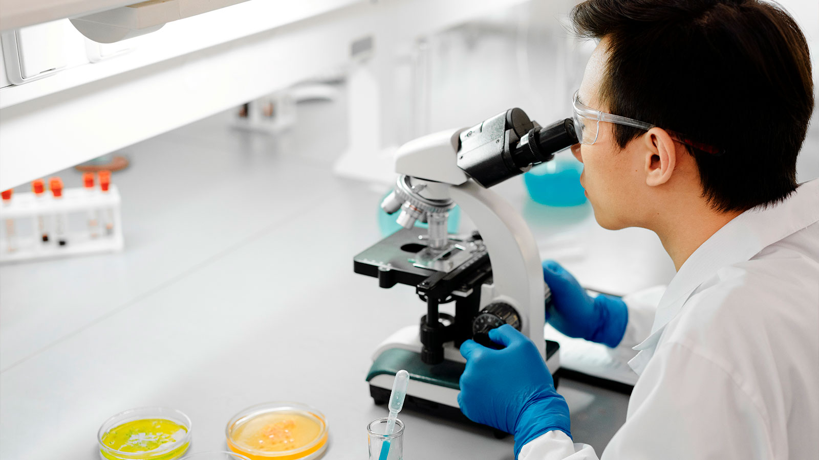 A man examining fluid under a microscope in a lab