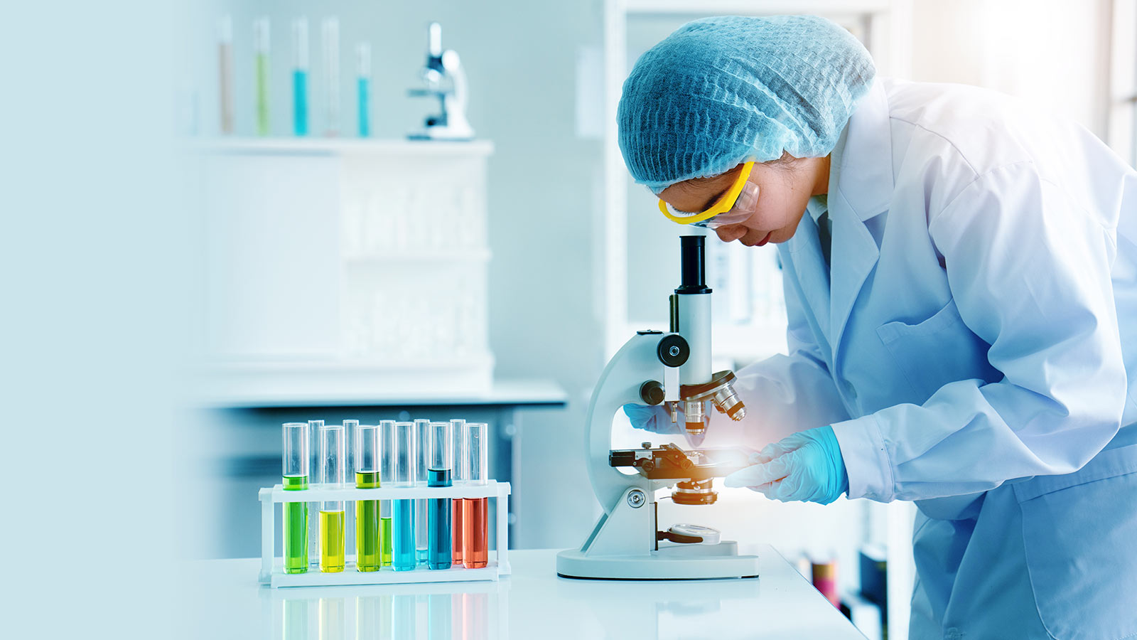 A woman working in a lab, examining fluid under a microscope