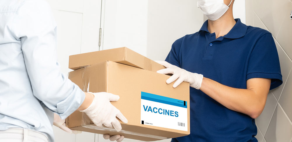Woman handing a box of frozen vaccines to a man in gloves.